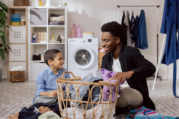 El hijo ayuda a papá con las tareas domésticas. El hombre clasifica la ropa, dobla la ropa, se prepara para secar y pasa tiempo juntos en el baño, enseñándole a la niña cómo usar la lavadora.