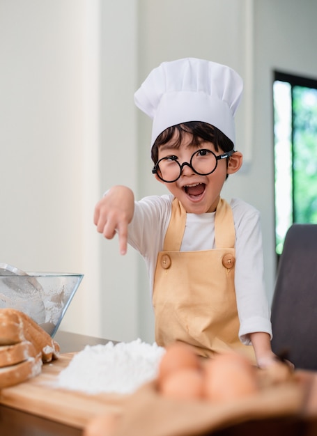 Hijo cocinando comida. Preparando un ingrediente con harina y pan. Estilo de vida diario del niño en casa. Familia asiática en la cocina.