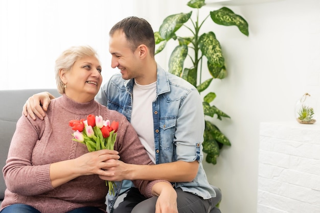 Hijo dando madre flores tulipanes.