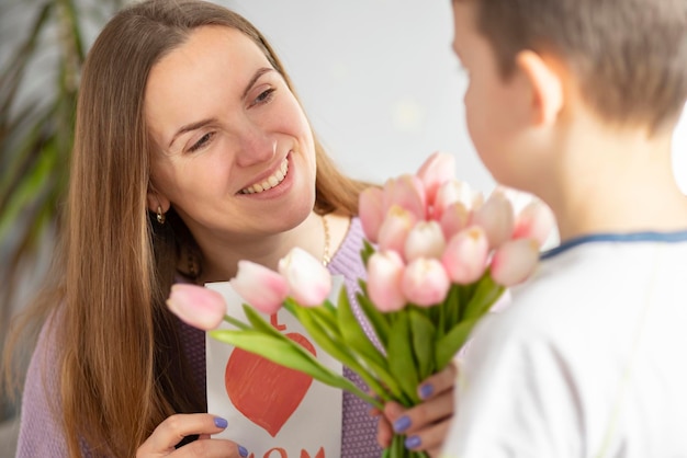 Hijo dando a su madre un ramo de tulipanes para felicitarla por el día de la madre