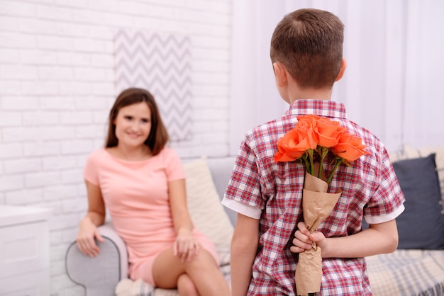 Hijo escondiendo rosas para su madre a sus espaldas