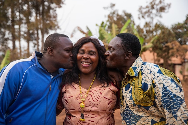 El hijo y el esposo de la familia africana feliz le dan un beso a la madre en el medio