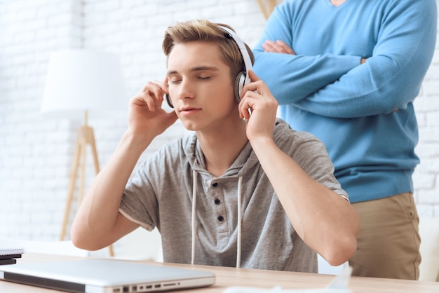 El hijo está escuchando música en los auriculares.