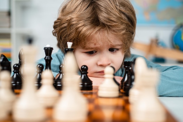 El hijo está jugando al ajedrez y sonriendo en casa Desarrollo temprano de los niños Niño jugando al ajedrez en casa Retrato de cerca cara graciosa