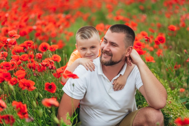 Hijo feliz jugando con su padre en verano en el campo de amapolas Familia divirtiéndose