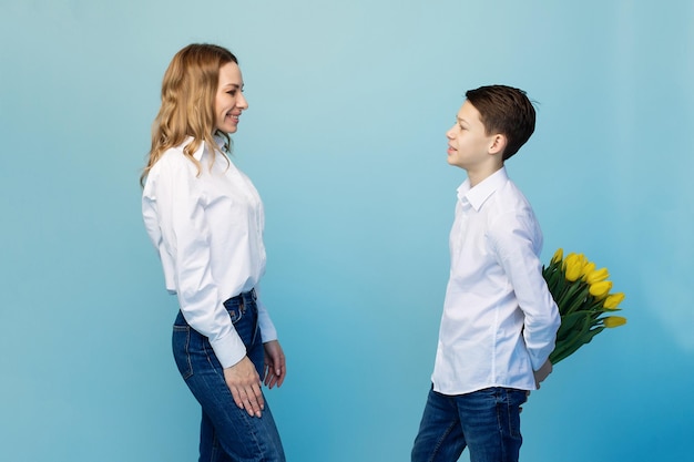 Un hijo gentil felicita a una madre feliz y le da un ramo de tulipanes.