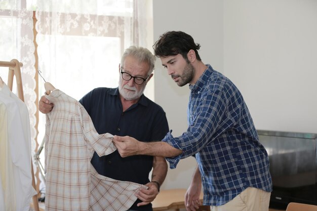 El hijo inconformista adulto y el padre mayor se quedan para trabajar en casa dos generaciones tienen barba hablando juntos y relajándose con una sonrisa felices disfrutan viviendo en cuarentena de aislamiento en casa el día del padre