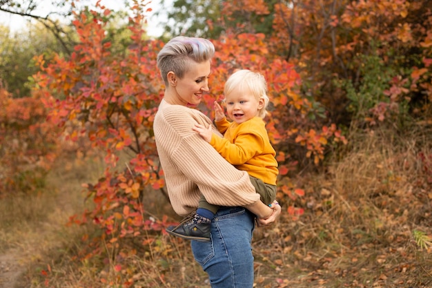 Hijo con madre en el fondo del parque otoño con árboles dorados