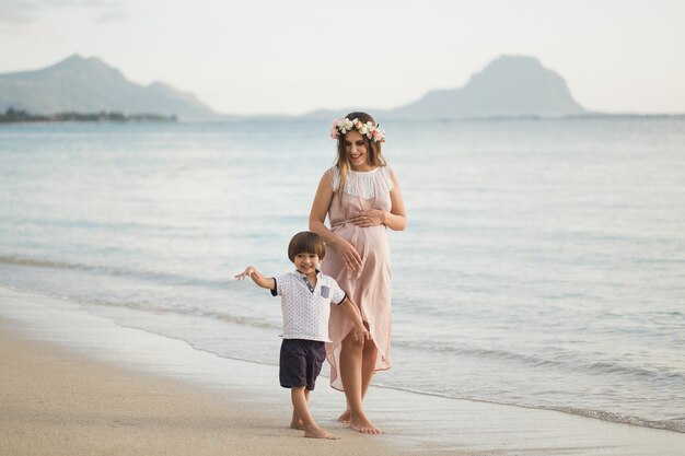 Hijo y mamá embarazada en la playa.