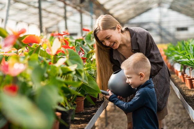 Hijo y mamá regando flores en invernadero