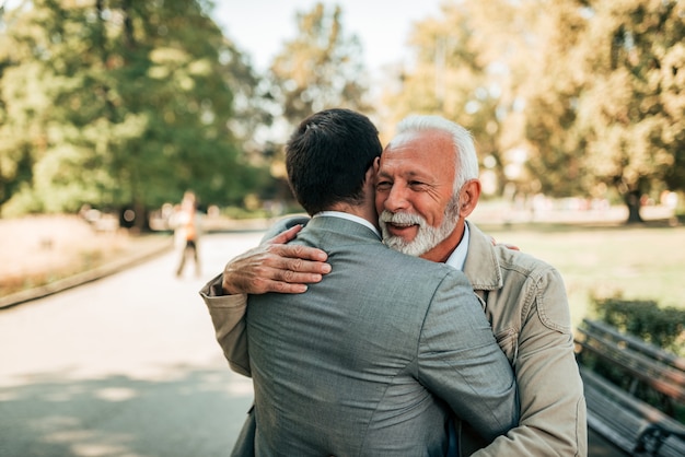 Hijo mayor del padre y del adulto que abraza en el parque.