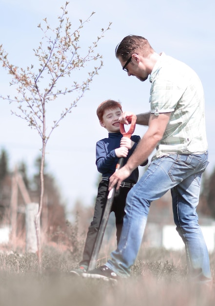 Hijo y padre plantan un árbol y hablan.