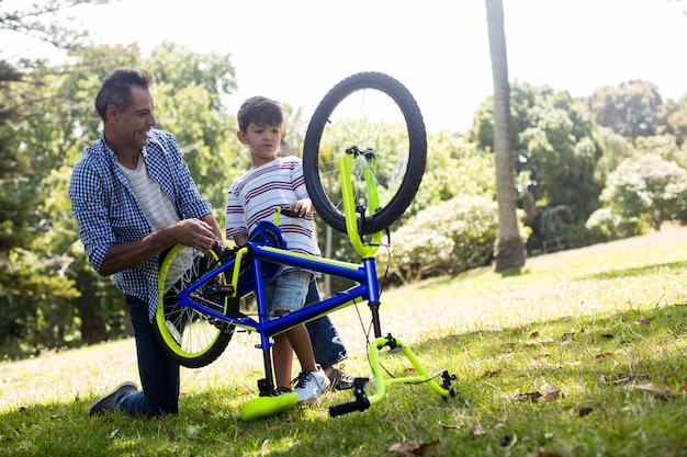 Hijo y padre reparando su bicicleta en el parque