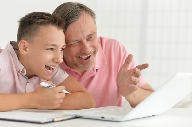 Foto hijo y padre usando laptop en casa