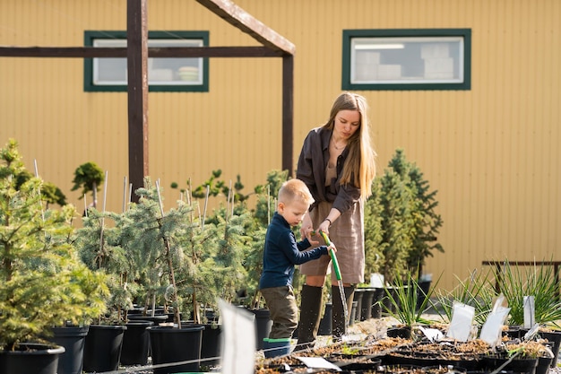 El hijo pequeño ayuda a mamá a regar las macetas de las plantas.