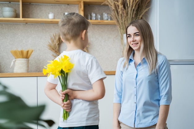 el hijo pequeño le da flores a mamá el 8 de marzo flores en manos de un niño narcisos amarillos