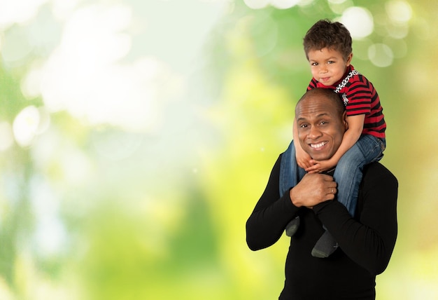 Hijo sobre los hombros de su padre sobre fondo verde claro