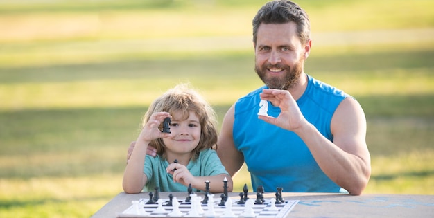 Hijo tendido en la hierba y jugando al ajedrez con el padre hijo jugar al ajedrez