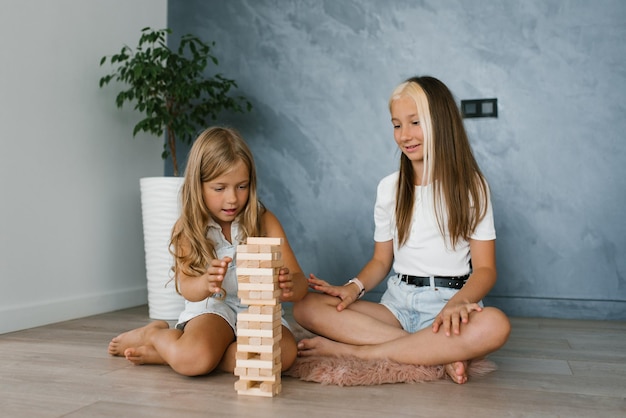 Los hijos de dos hermanas juegan con entusiasmo a construir una torre con bloques de madera en casa