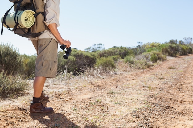 Hiker que prende seus binóculos na trilha do país