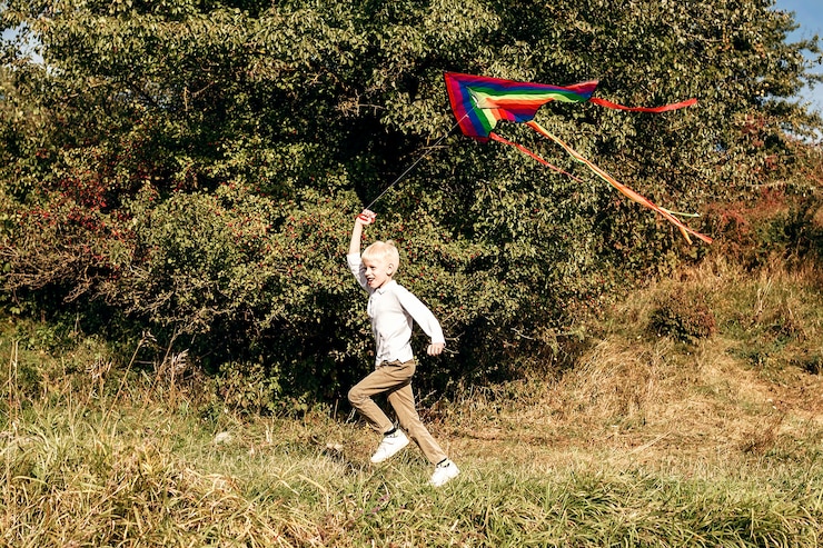 Foto hild feliz correndo pelo gramado com uma pipa kid com pipa no prado