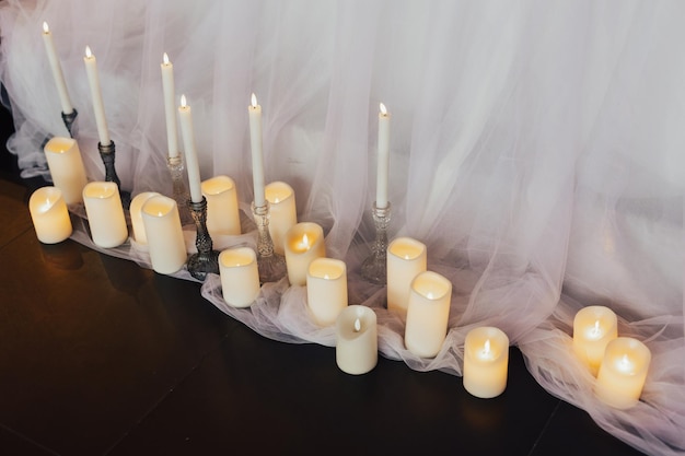 Una hilera de velas sobre un suelo negro con una cortina detrás.