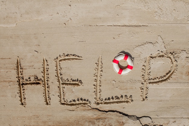 Hilfe Inschrift auf dem Sand mit Ringboje