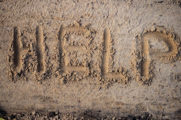 Hilfe Inschrift in Buchstaben auf Sand Ansicht von oben Hilferuf