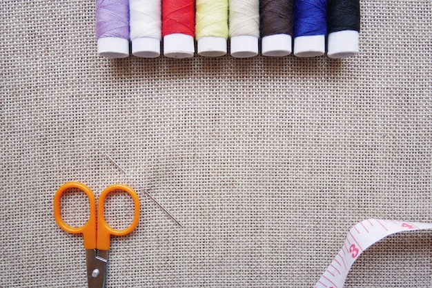 Hilo de colores, tijeras, cinta métrica y alfileres en tela de lino