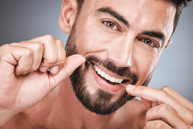 Hilo dental limpieza de dientes y retrato de hombre en estudio para belleza cuerpo saludable e higiene en el fondo Modelo masculino hilo dental y boca para sonrisa facial aliento fresco y bienestar dental feliz