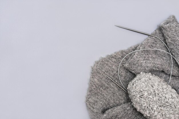 hilo de tejer gris en una madeja con agujas y una bufanda sobre fondo gris imagen monocromática de moda pasatiempo relajante y ocio para todos hilo de lana para ropa de invierno hecha a mano