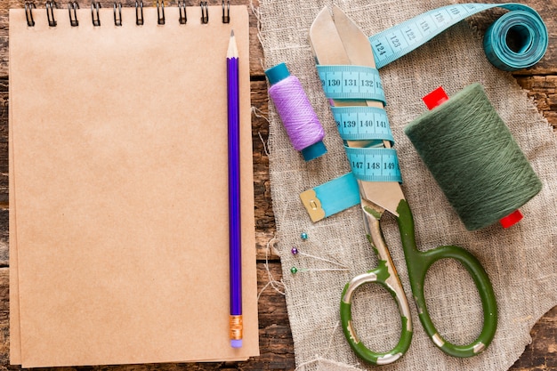 Hilo, tijeras, cinta métrica y un cuaderno para notas sobre la madera.