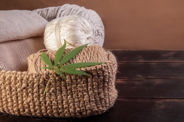 Hilos, hilados y tejidos hechos de cáñamo con hoja de Cannabis sobre fondo de madera.