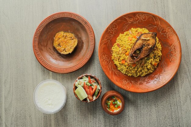 Hilsa Khichuri Combo con ensalada de berenjena borhani y boondi rabi servido en un plato aislado en la vista superior de la alfombra de la comida india y bangladeshí