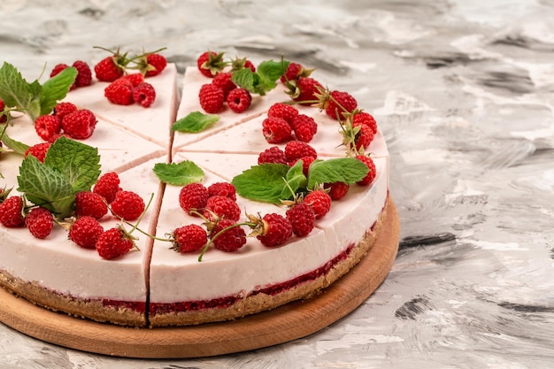 Himbeer-Käsekuchen-Creme-Mousse-Torte, verziert mit frischen Beeren und Minzkopienraum