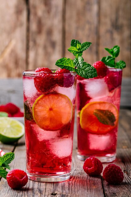 Himbeer-Mojito-Limonade mit Limette und frischer Minze im Glas auf Holzhintergrund Erfrischender Sommercocktail