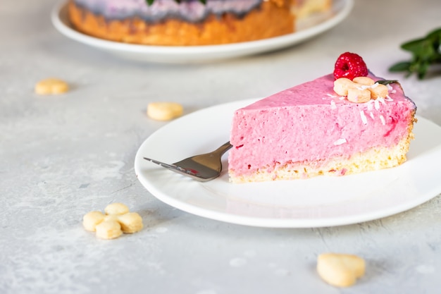 Himbeer-Sahne-Mousse-Torte mit Himbeeren, Minikeksen und Kokosflocken dekoriert