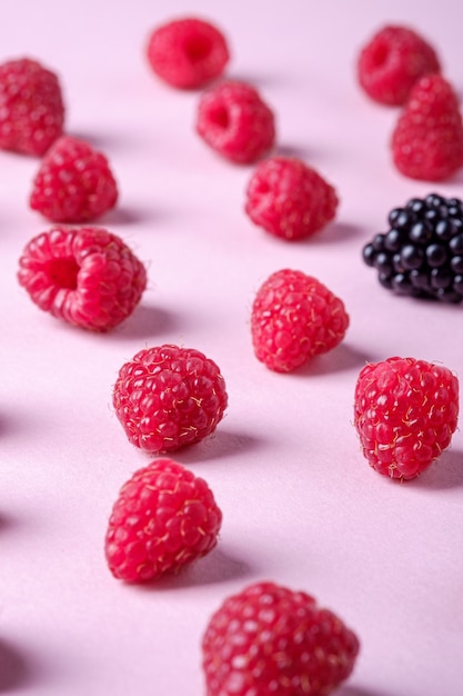 Himbeer süße organische saftige Beeren mit einzelnen Brombeeren, Muster, Textur, auf rosa Papierwand, Makro