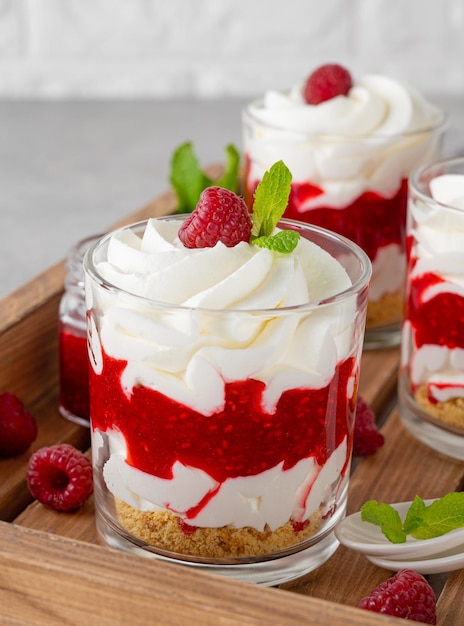 Foto himbeer-trifle mit schlagsahne, beerensauce, kekskrümeln und minze in einem glas