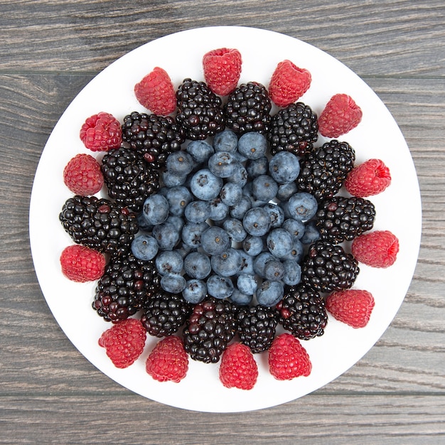 Himbeeren, Blaubeeren und Brombeeren auf einem weißen Teller. Vitamin- und Diätnahrung