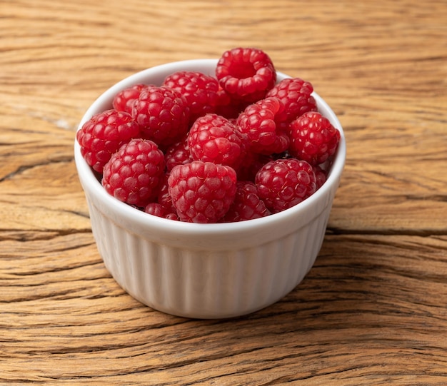 Himbeeren in einer Schüssel über Holztisch