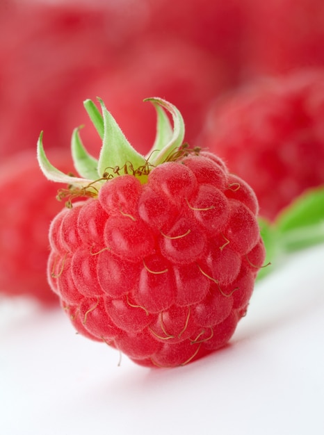 Himbeeren mit grünen Blättern. Dieses Bild ist auf eines von ihnen fokussiert