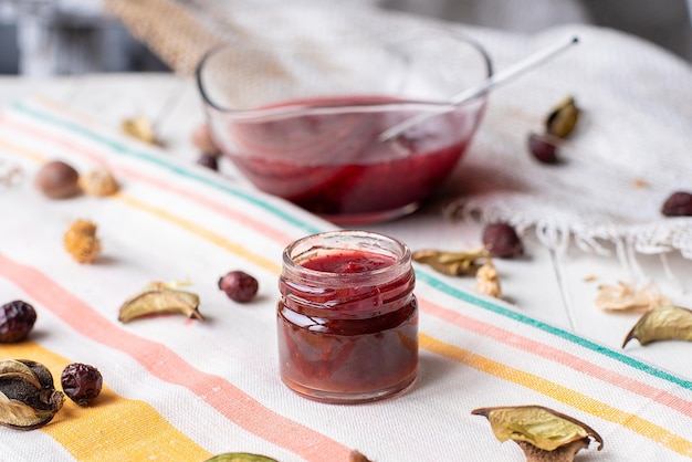 Himbeermarmelade auf dem Tisch ein Glas rote Marmelade auf hellem Stoff