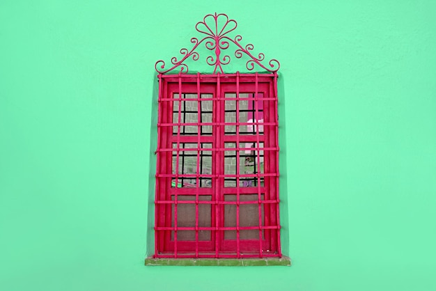 Himbeerrotes schmiedeeisernes Vintage-Fenster an mintgrüner Wand