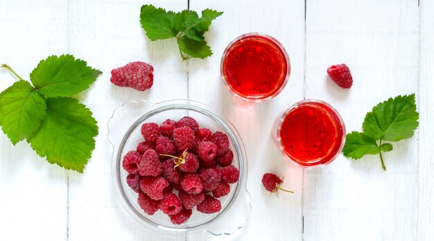 Himbeersaft in Gläsern und frischen Beeren