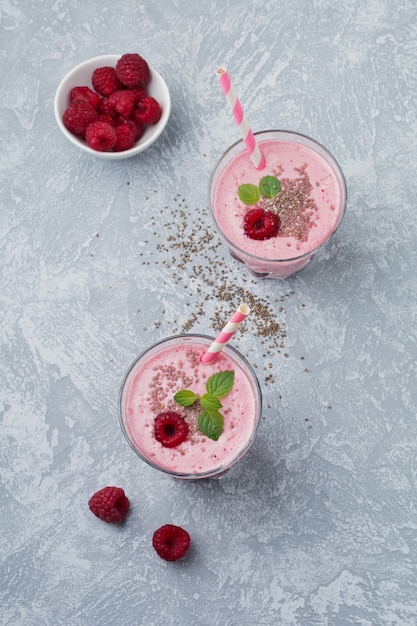 Himbeersmoothie mit Chiasamen und Minze in einer Glasschale auf einem grauen hellen Stein- oder Betontisch. Gesundes und leckeres Frühstück. Selektiver Fokus.