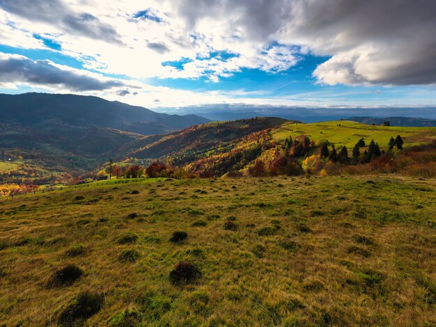 Himmel mit weißer und flauschiger Wolkenschicht über grünen Herbsthügeln, Panorama-Drohnenaufnahme aus der Luft