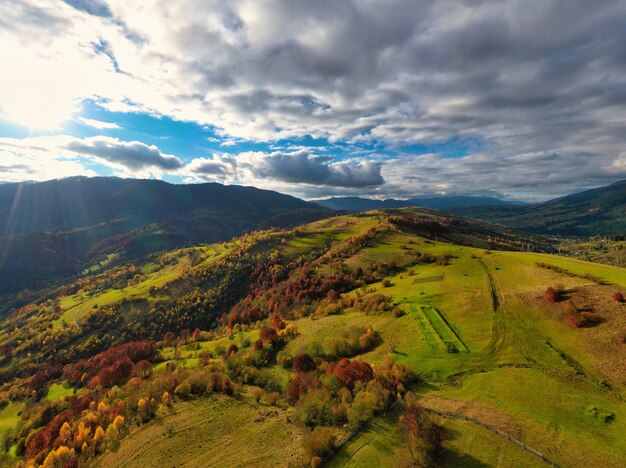 Himmel mit weißer und flauschiger Wolkenschicht über grünen Herbsthügeln, Panorama-Drohnenaufnahme aus der Luft