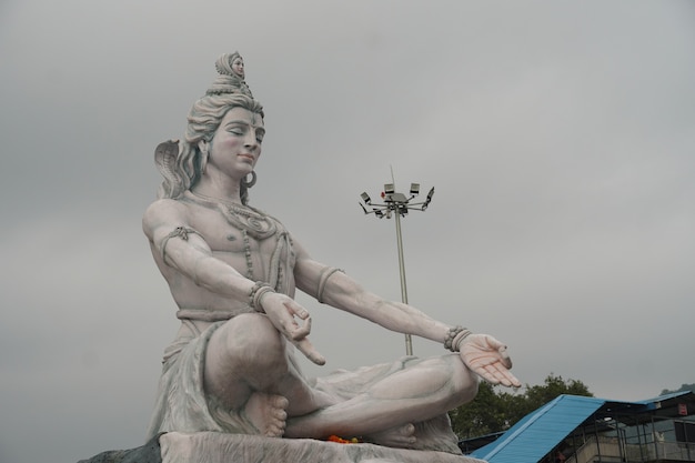 Foto hindu-gott shiva skulptur sitzen in meditation am fluss ganges in rishikesh, indien,