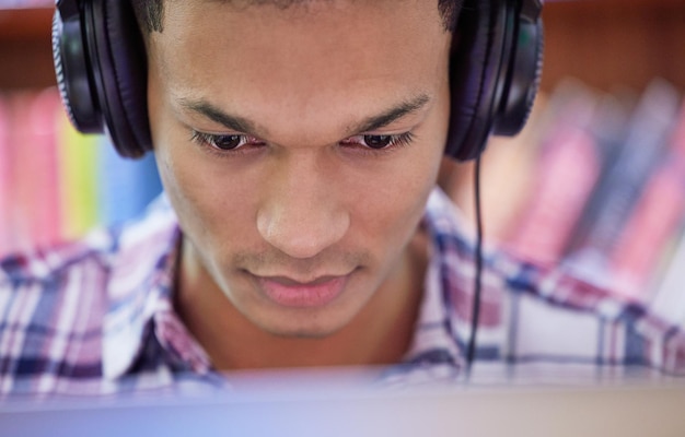 Hingabe macht es möglich Aufnahme eines jungen Mannes, der einen Computer in einer Universitätsbibliothek benutzt